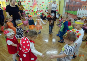 Dzieci tańczą w kole w jesiennych przebraniach.